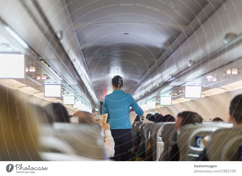 Innenraum eines Verkehrsflugzeuges mit Stewardess, die die Passagiere  während des Fluges auf den Sitzen bedient. - ein lizenzfreies Stock Foto  von Photocase