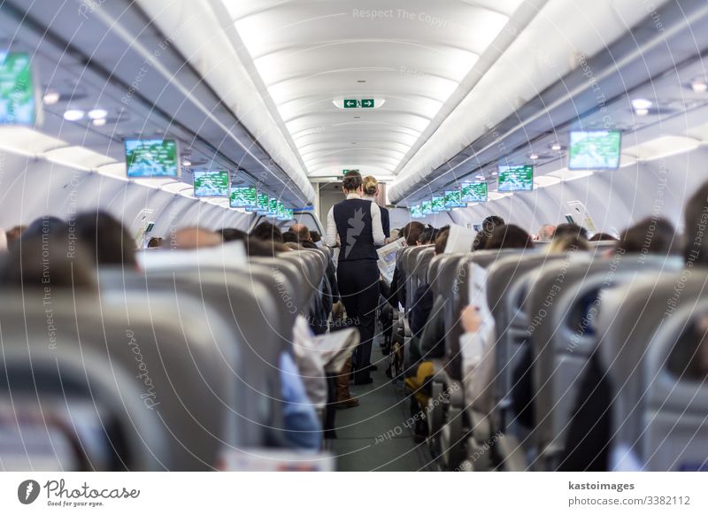 Innenraum eines Verkehrsflugzeuges mit Stewardess, die die Passagiere während des Fluges auf den Sitzen bedient. Flugbegleiterin Flugzeug Fluggerät Innenbereich