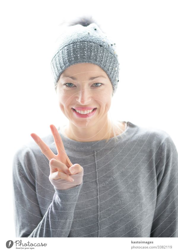 Nahaufnahme eines Porträts einer fröhlichen kaukasischen Frau, die ein Friedenszeichen gestikuliert und lächelt Zeichen Mädchen schön Glück Hut Lächeln weiß
