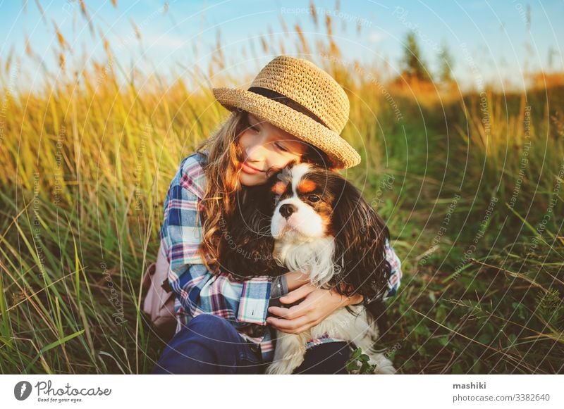 fröhliches Mädchen, das mit seinem Hund die Sommerferien genießt und auf der sonnigen Wiese spazieren geht und spielt. Reisen, Erkundung neuer Orte und ländliches Wohnkonzept