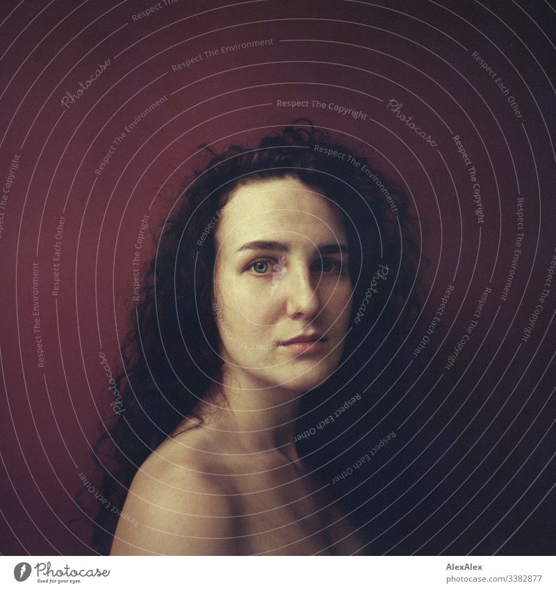 Analoges Portrait einer jungen Frau vor roter Wand Blick in die Kamera Porträt Zentralperspektive Schwache Tiefenschärfe Kunstlicht Tag Textfreiraum rechts
