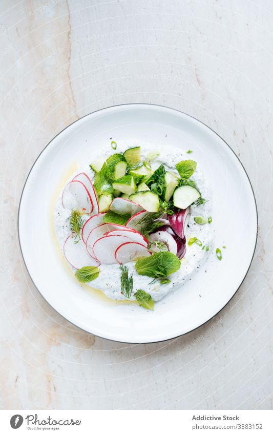 Radieschensalat mit Zucchini, roten Zwiebeln und saurer Sahne im Teller Rettich Salatbeilage Kraut Lebensmittel frisch lecker geschmackvoll Gemüse Speise