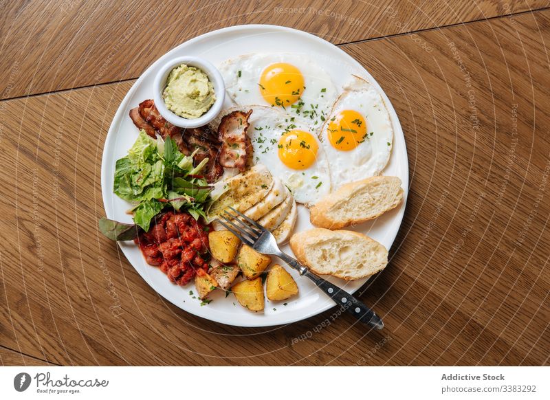 Leckere Frühstücksmahlzeit mit Spiegeleiern und Gemüse Englisch Ei gebraten Zuprosten Speck Bohne Kartoffel Salatbeilage Küche Speise Teller Tisch Kalorie
