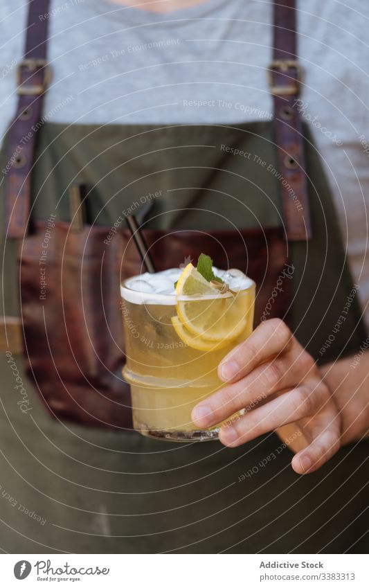 Person mit einem Glas Cocktail, dekoriert mit in Scheiben geschnittener Zitrone und Minze Limonade trinken Getränk lecker geschmackvoll frisch kalt Saft Stroh