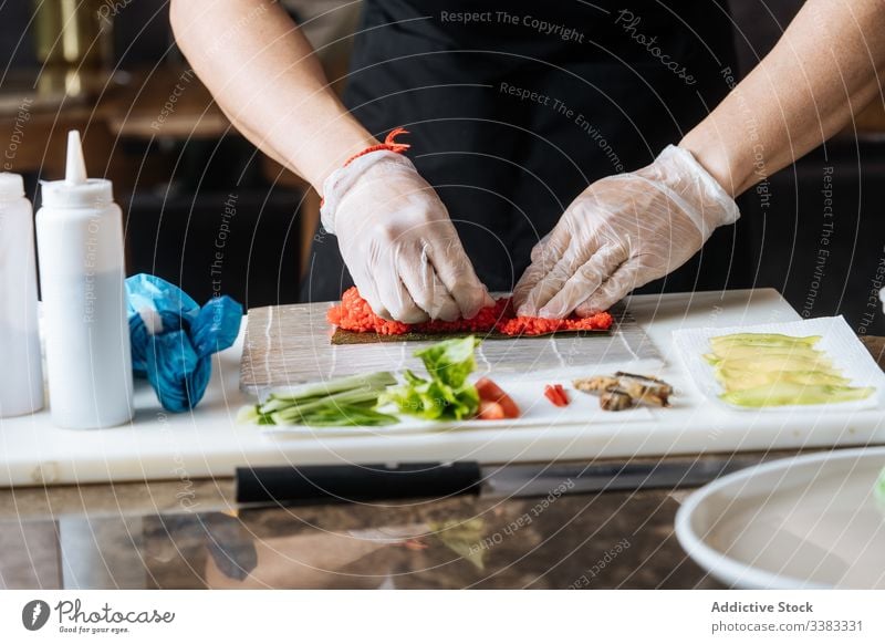 Koch, der Sushi mit Lebensmittelzutaten auf dem Tisch zubereitet Meeresfrüchte Vorbereitung frisch Bestandteil lecker Speise geschmackvoll Fisch rollen