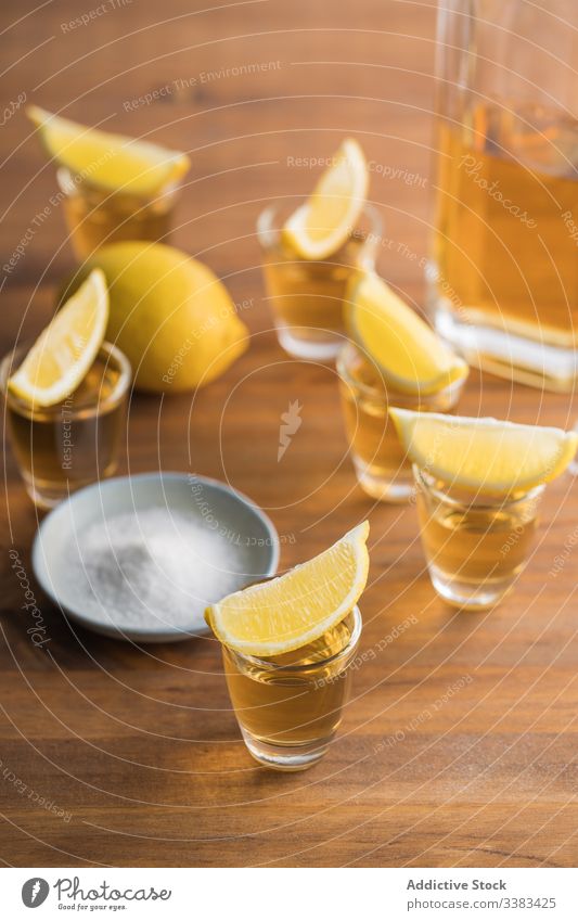 Tequila in Shots mit Salzrand und Zitrone Alkohol Schuss Rand Schnaps Tisch hölzern Glas Getränk trinken frisch geschmackvoll Zitrusfrüchte orange Party lecker
