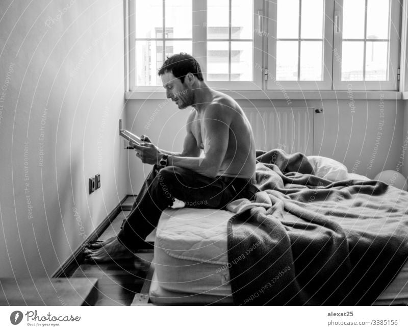 Mann liest in seinem Schlafzimmer in Schwarz-Weiß entspannend lernen Wissen Bett jung Lügen heimwärts männlich gutaussehend Buch Lifestyle Person Erwachsener