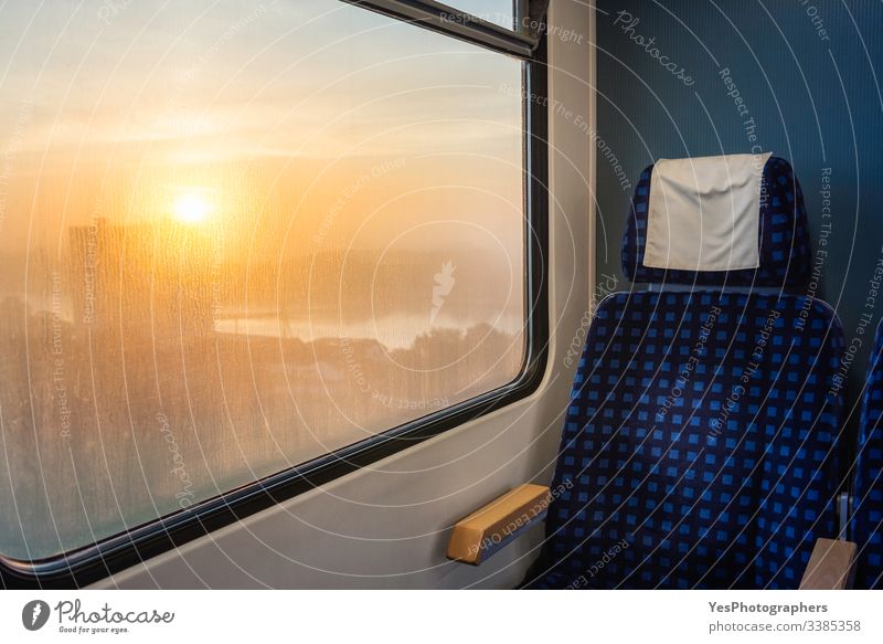 Zuginnenraum mit Stuhl und Sonnenaufgangsansicht am Fenster. Zugfahren Deutscher Zug Deutschland blauer Stuhl Wagen bequem Arbeitsweg umweltfreundlich