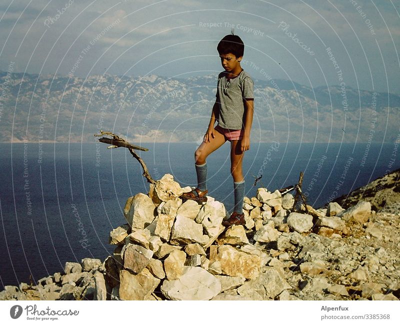 Junges attraktives Kind besteigt einen Berg mit einem Stock in Unterhose Berge u. Gebirge Bergkette Bergkamm blau wandern Bergsteigen Natur Landschaft Abenteuer