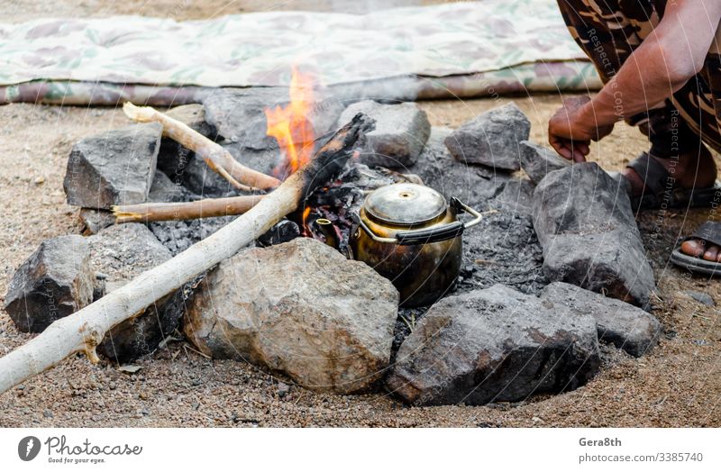 alter Kessel am Feuer und Menschen, die neben ihm sitzen in Ägypten Dahab Süd-Sinai Beduinen-Tee Naher Osten Brandasche sich[Akk] sonnen Bettler gebrochen