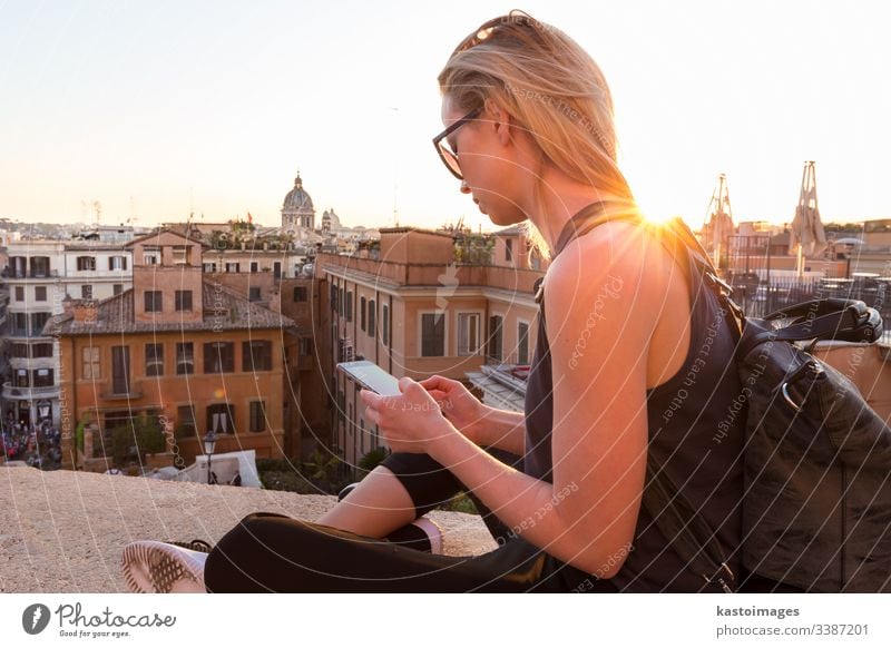 Touristin, die eine Handy-Reise-App in der Nähe der Piazza di Spagna nutzt, dem Wahrzeichen des Platzes mit den spanischen Stufen in Rom, Italien bei Sonnenuntergang.
