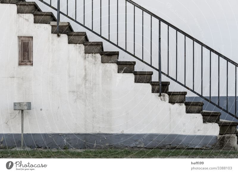 Treppe mit Geländer und Aschenbecher vor dreckiger Wand diagonal Baustein minimalistisch Stufenordnung Treppenansatz Steinwand Ordnung Linien Muster