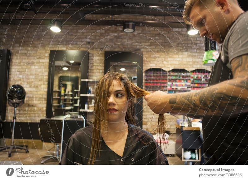 Kaukasische Frau lässt sich in einem hippen Friseursalon die Haare frisieren Themen der Friseurin verwöhnende Glamour-Haarpflege Haarschnitt Salon Hipster