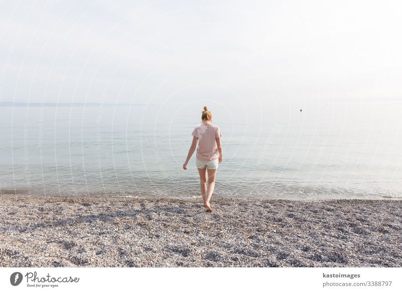 Fröhliche sorglose Frau genießt den Sonnenuntergangsspaziergang am weißen Pabbled Beach. Strand MEER Mädchen Glück Natur jung Sommer Wasser Meer schön Urlaub