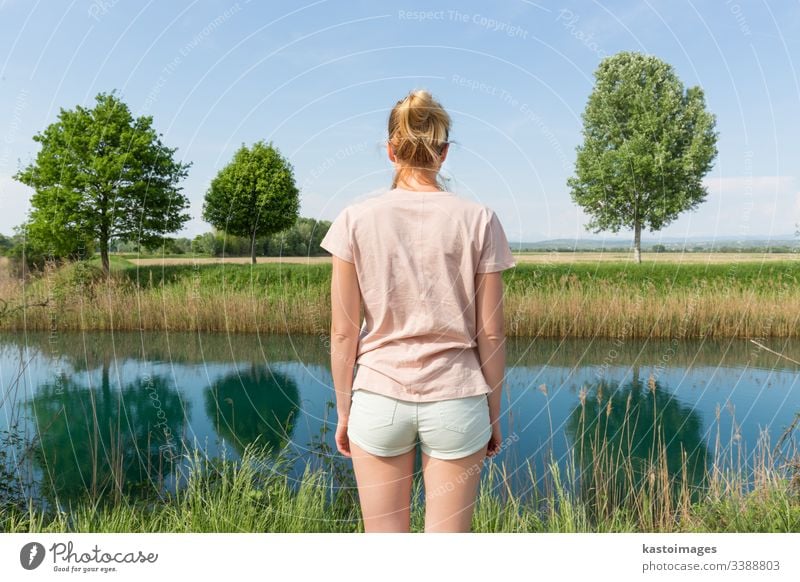 Junge Frau in lässiger Sommerkleidung, die eine schöne Aussicht auf die friedliche Landschaft genießt. Natur Wiese Rückseite jung Schönheit Tag grün Gesundheit