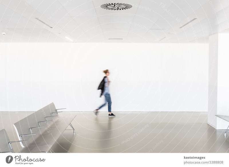 Bewegungsunschärfe einer Frau, die in einem zeitgenössischen weißen, leeren Flur geht Innenbereich Architektur Sitze Terminal modern Raum Kaukasier verschwommen