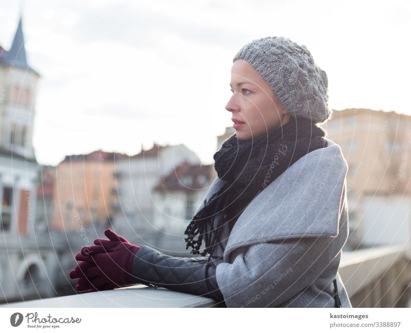 Porträt einer schönen jungen Frau mit Blick auf den Fluss Ljubljanica in Ljubljana, Slowenien, im Winter kalt Dame Mantel Handschuhe Verschlussdeckel Einfrieren