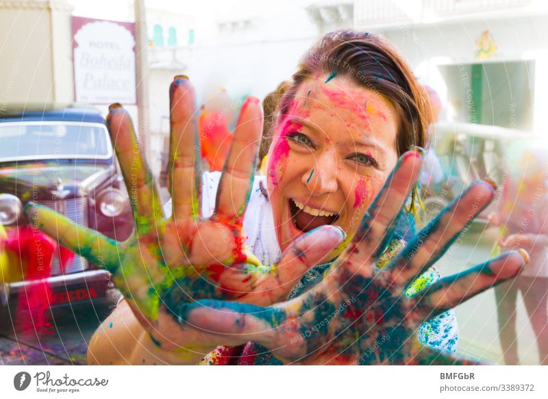 Frau, die sich am Holi-Festival amüsiert und ihre farbigen Hände in die Kamera zeigt aufgeregt verrückt genießend Fest der Farben Tourismus Konzept Fröhlichkeit