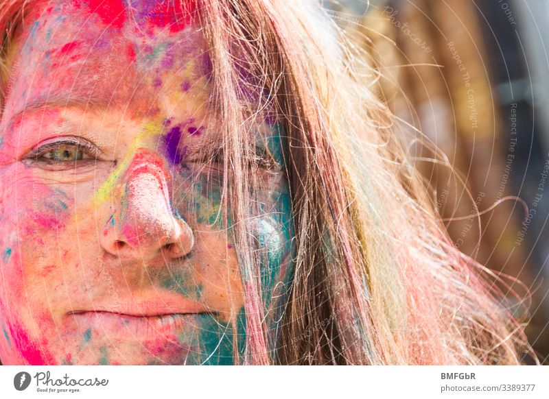 Porträt einer glücklichen Frau mit Farben vom heiligen Fest im Gesicht aufgeregt verrückt genießend Fest der Farben Tourismus Konzept Fröhlichkeit Sommer Spaß