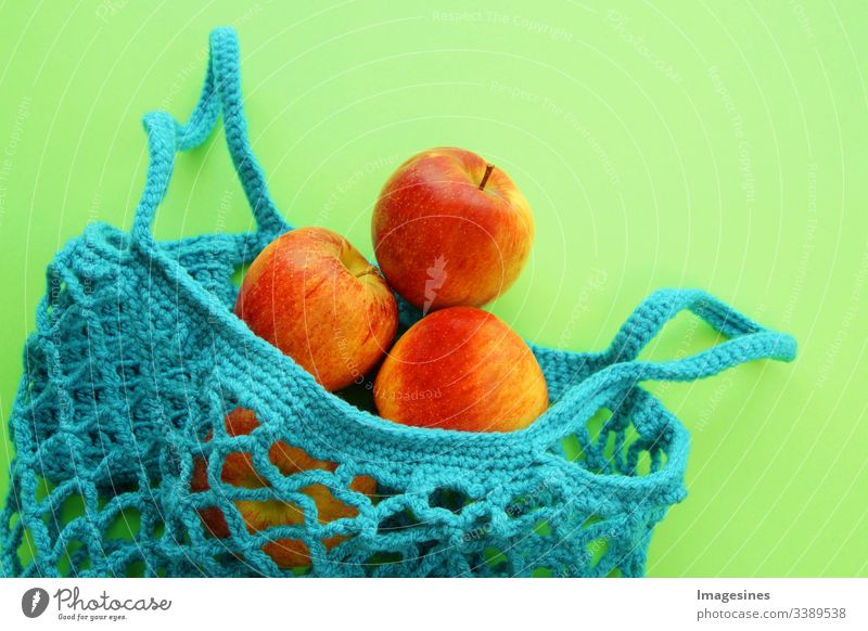 Einkaufsnetz aus Baumwolle - Frei von Kunststoff. wiederverwendbarer Einkaufsbeutel mit Obst - Äpfeln auf grünem Hintergrund. Null Abfall und Ökologie Konzept. umweltfreundlicher Käufer. Ansicht von oben