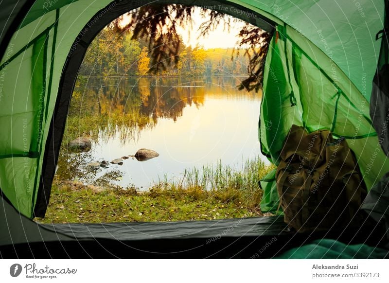Blick aus dem Inneren eines Touristenzeltes mit Rucksack. Wunderschöne skandinavische Wald- und Seenlandschaft. Finnland aktiv Aktivität Abenteuer Herbst Lager