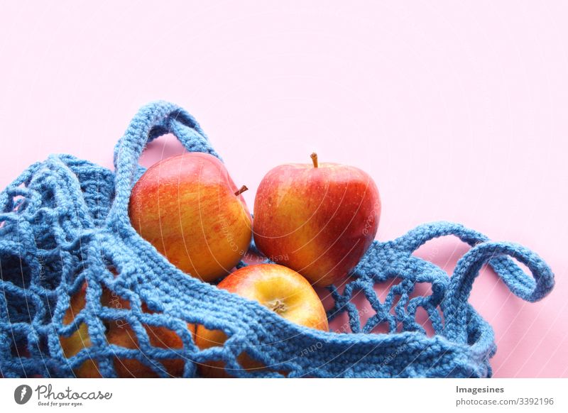 Einkaufsnetz aus Baumwolle - Frei von Kunststoff. wiederverwendbarer Einkaufsbeutel mit Obst - Äpfeln auf rosa Hintergrund. Null Abfall und Ökologie Konzept. umweltfreundlicher Käufer. Ansicht von oben