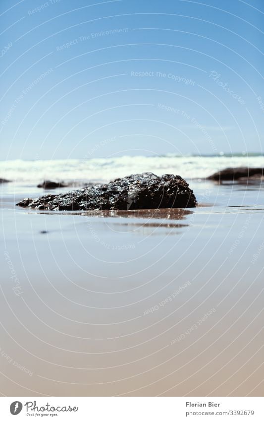 Ein kleines Stück Gestein welches in der Brandung aus dem Sand ragt Stein Felsen Insel Strand Meer Urlaub mediterran Wellen Fantasie Küste Wasser