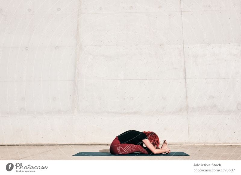 Anonyme Frau, die ihren Körper in sitzender Vorbeugeposition streckt Straße Dehnung Yoga sitzende Vorwärtsbeuge üben heiter beweglich gymnastisch Training
