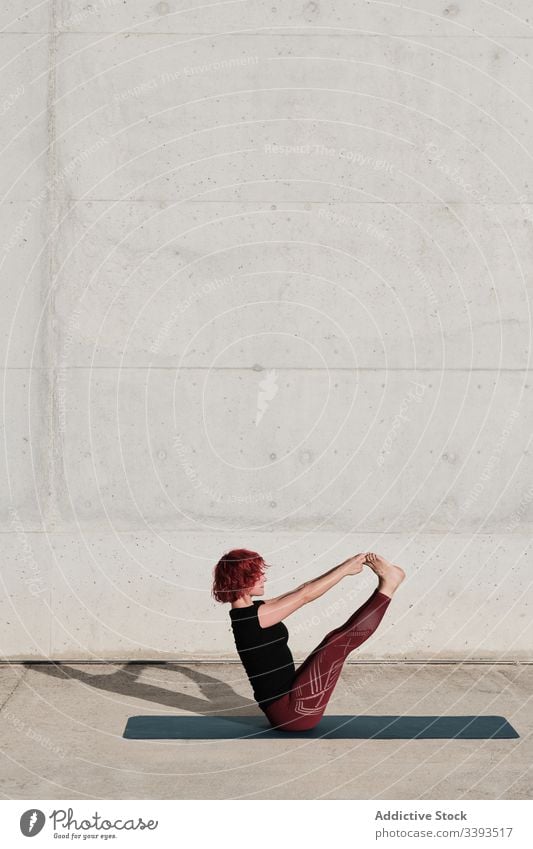 Flexible junge Sportlerin praktiziert Yoga im Gleichgewicht paripurna navasana auf der Strasse Straße Boot-Pose beweglich Übung Dehnung Frau akrobatisch üben