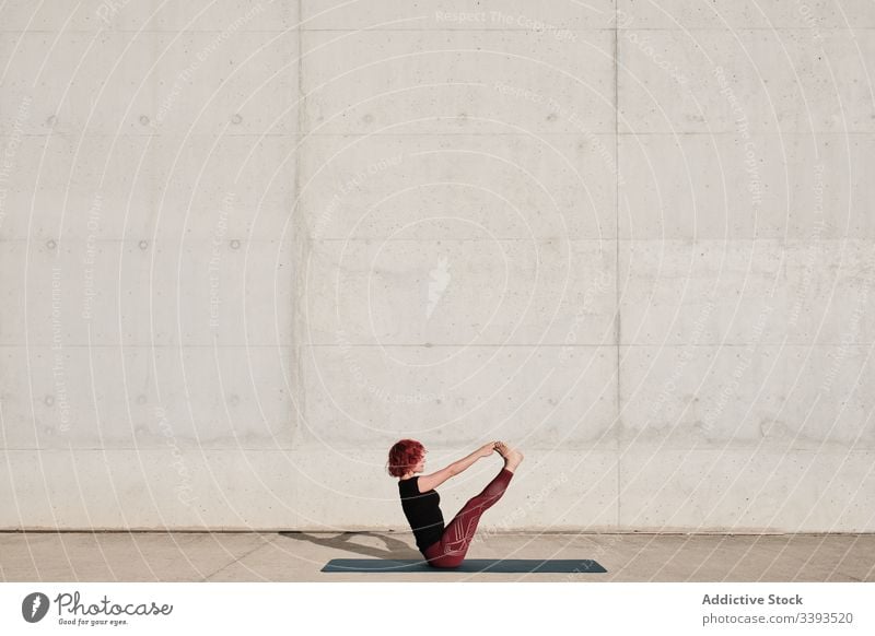 Flexible junge Sportlerin praktiziert Yoga im Gleichgewicht paripurna navasana auf der Strasse Straße Boot-Pose beweglich Übung Dehnung Frau akrobatisch üben