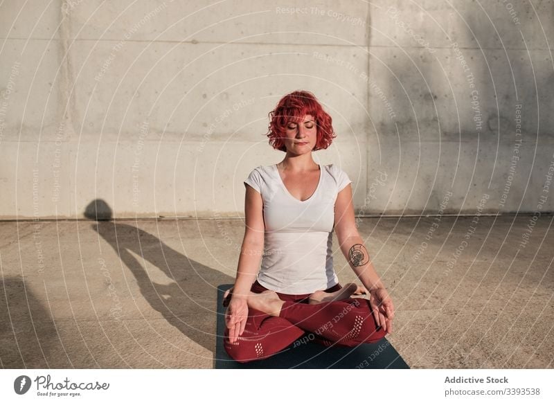 Frau mit geschlossenen Augen meditiert in Lotus-Pose auf der Straße bei Sonnenuntergang meditieren Yoga ruhig üben gyan mudra beweglich idyllisch gymnastisch