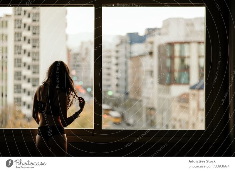 Nicht erkennbare junge Frau in Dessous am Fenster sinnlich träumen Stadtbild verführerisch sensibel schlank Haare berühren feminin Angebot Versuchung