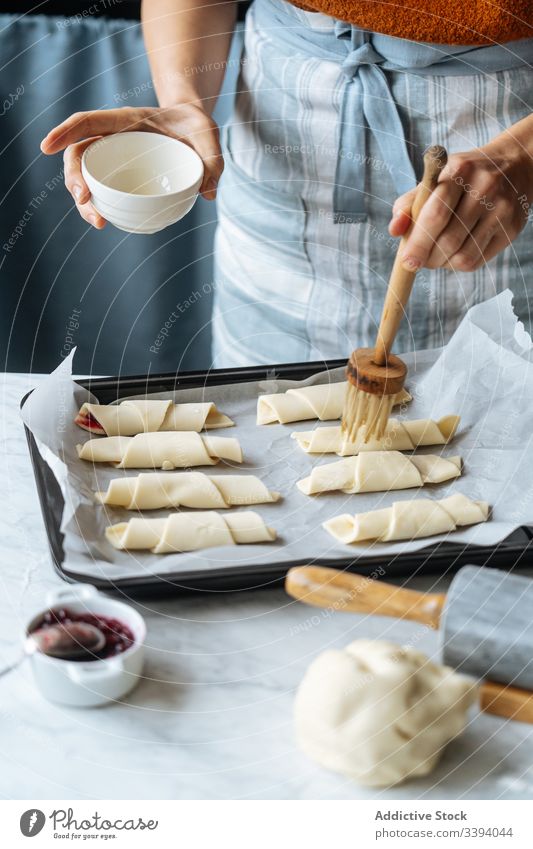 Koch hält Schüssel und streicht Croissants in Backblech auf Tisch bürstend Marmelade Teigwaren Schalen & Schüsseln Vorbereitung aufgeschnitten Bäckerei