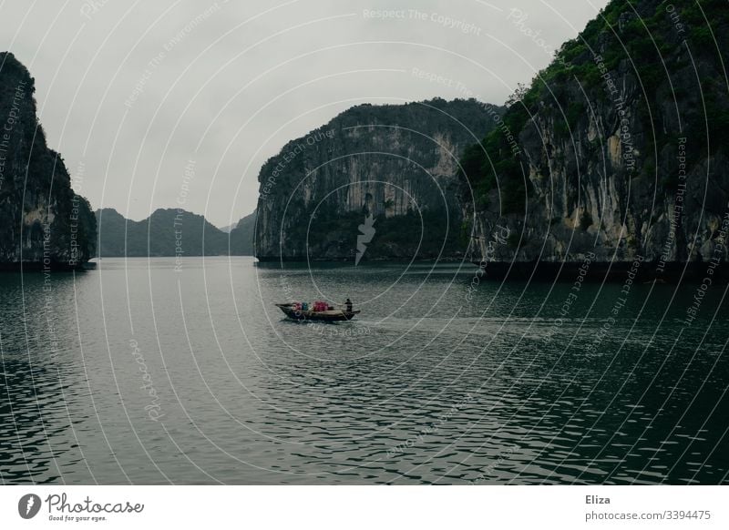 Ein Fischerboot auf dem Meer in der Halong Bay in Vietnam; schöne Landschaft mit Kalksteinfelsen, die aus dem Meer ragen, bei nebligem Wetter Sehenswürdigkeit