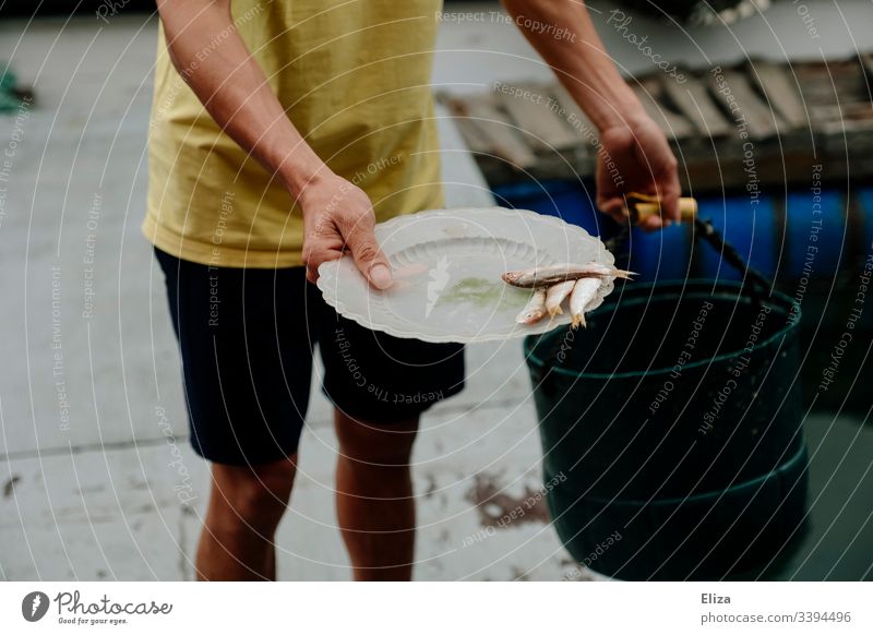 Ein Fischer hält einen Teller mit Fischen in der Hand Fischerei Fischzucht Futter mann halten verfüttern Wasser Fischereiwirtschaft dokumentarisch Vietnam