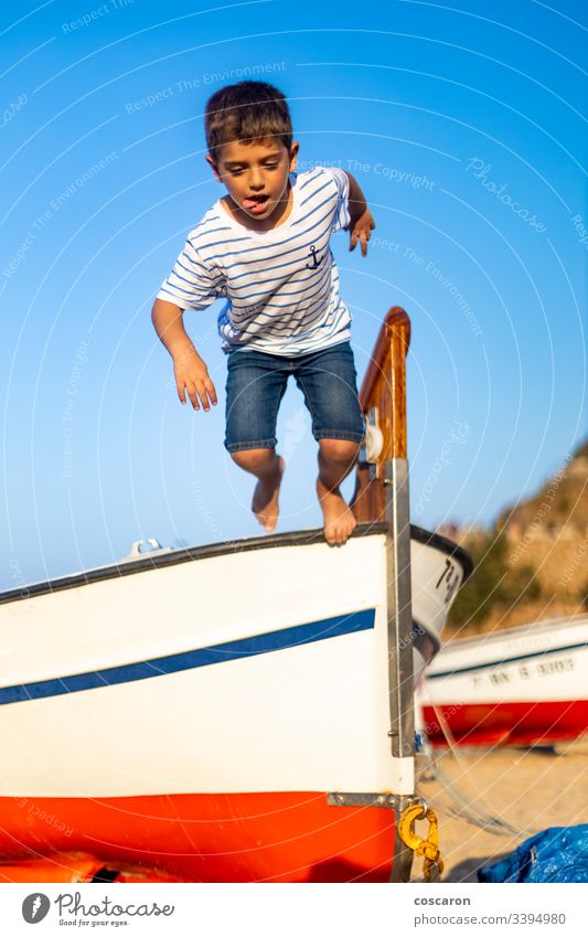 Kleines Kind, das aus einem Boot mit blauem Himmelshintergrund springt aktiv Air Hintergrund Strand schön Junge sorgenfrei heiter Kindheit Küste Küstenlinie