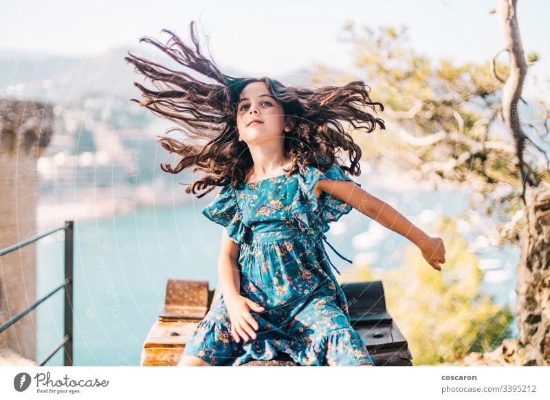 Lustiges kleines Mädchen, das sein langes Haar bewegt Aktivität bezaubernd die Arme weit geöffnet schön Schönheit Kaukasier schick Kind Kindheit Kleidung Küste