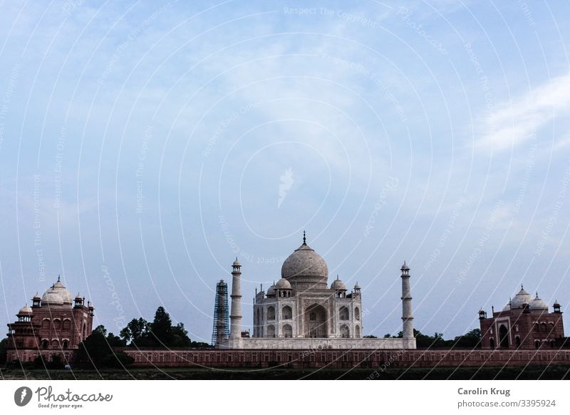 Das märchenhafte Taj Mahal mit seinen beiden Nebengebäuden. Fast so, als würden die beiden Nebengebäude aus Sandstein die wunderbare Königin, das Grabmal einer großen Liebe, wachen.  Eine Totale von der anderen Seite des heiligen Yamuna-Flusses