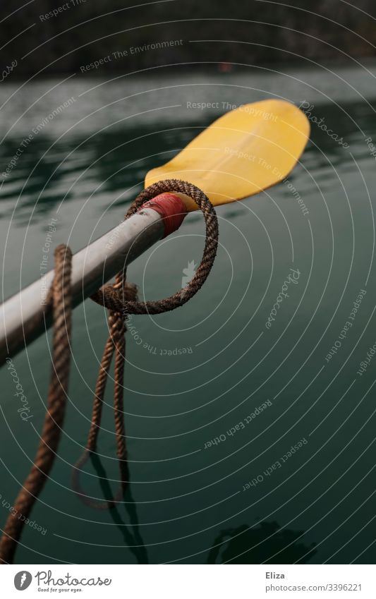 Ein gelbes Paddel, mit einem Seil umwickelt, schwebt über grünem Wasser Kajak Meer Sport rudern Bewegung Außenaufnahme Ferien & Urlaub & Reisen Wassersport