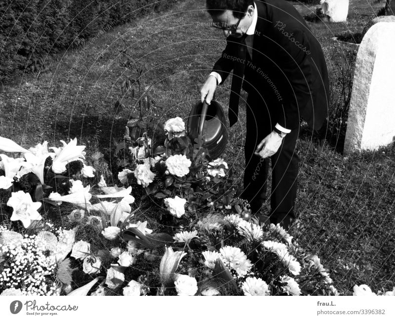 Etwas konnte für den alten Mann noch getan werden, dachte er, und goss die Blumen auf dem frischen Grab. Friedhof Trauer Beerdigung Außenaufnahme Tod