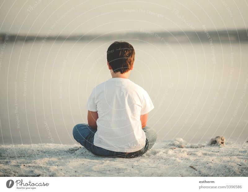 Rückenansicht eines nachdenklichen Kindes, das am Strand sitzt Kindheit nostalgisch Gedanke Einsamkeit einsam Ausdruck Freiheit Unschuld Porträt ernst träumen