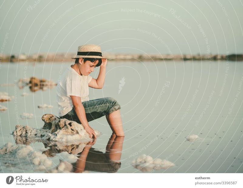 trauriger und nachdenklicher Junge, der am Strand sitzt Kind Kindheit nostalgisch Gedanke Einsamkeit einsam Ausdruck Freiheit Unschuld Porträt ernst träumen