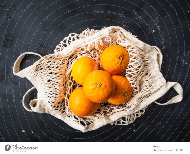 Draufsicht auf frische Orangen in einer wiederverwendbaren Einkaufstasche auf einem schwarzen Hintergrund orange Frische einkaufstasche draufsicht orange Farbe