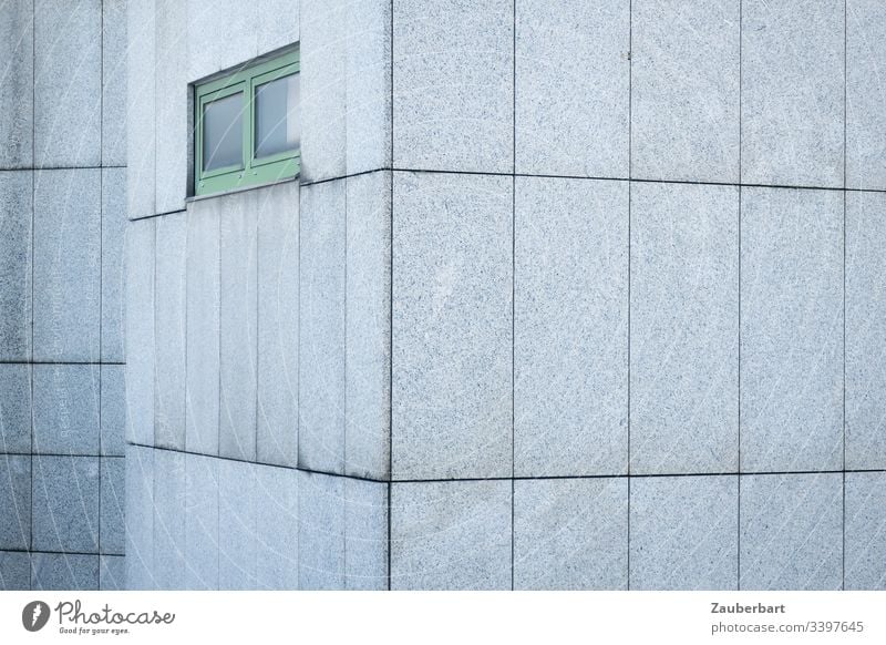 Graue Fassade aus Granitplatten mit grünem Fenster in trostloser Schönheit Haus grau Platten Fugen Muster Rechteck trist menschenleer Außenaufnahme Gebäude