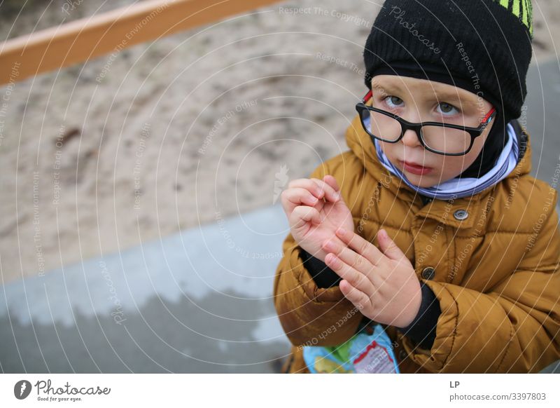 Junge, der in die Kamera schaut und seine Hand zeigt Blick in die Kamera beobachten neugierig nach unten Neugier Auge Kinderspiel Kindheitserinnerung