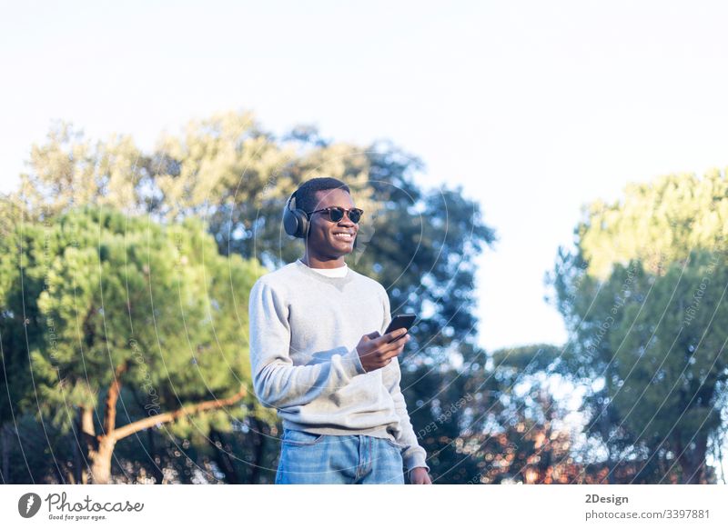 Afro-Jugendlicher, der ein Mobiltelefon benutzt. Stil Technik & Technologie 1 Lifestyle benutzend Einstellung männlich schwarz Straße Handy Freizeitkleidung