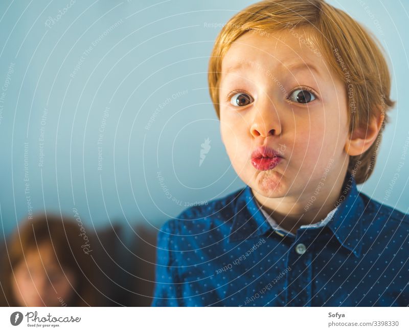 Kleiner blonder Junge mit komischem Gesichtsausdruck. Nahaufnahme-Portrait Kind wenig lustig Spaß Ausdruck Kaukasier Hemd blau Mode Auge Aussehen lebhaft Person