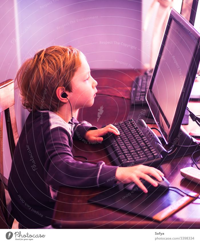 Süßer kleiner Junge spielt konzentriert am PC. Violetter Ton Computer Kind Technik & Technologie spielen Internet Freizeit männlich Person Lifestyle wenig Musik