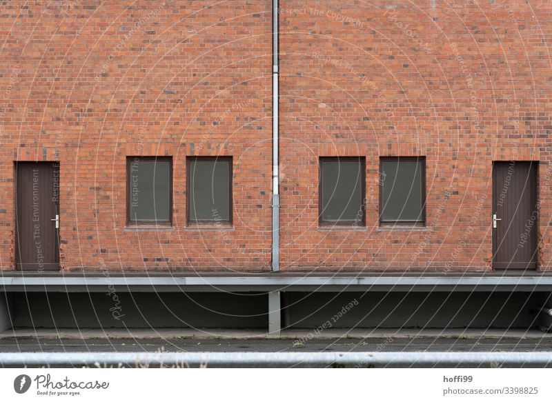 Symmetrische Rotklinker Fassade mit Fallrohr, Türen und Fenstern Klinkerfassade klinkerwand rotklinker Symmetrie Jalousie geschlossen Lagerhalle Lagerhaus Hafen