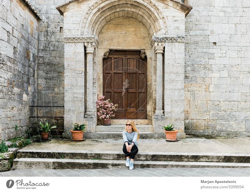 Junge Reisende sitzt auf den Stufen einer mittelalterlichen Kirche in der Toskana, Italien Erwachsener antik Antiquität Architektur Gebäude lässig katholisch